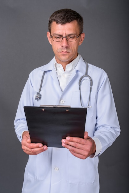 Médico guapo con el pelo corto sobre fondo gris