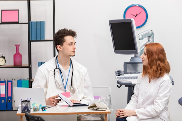 Foto un médico habla con una enfermera en su oficina mientras espera al siguiente paciente.