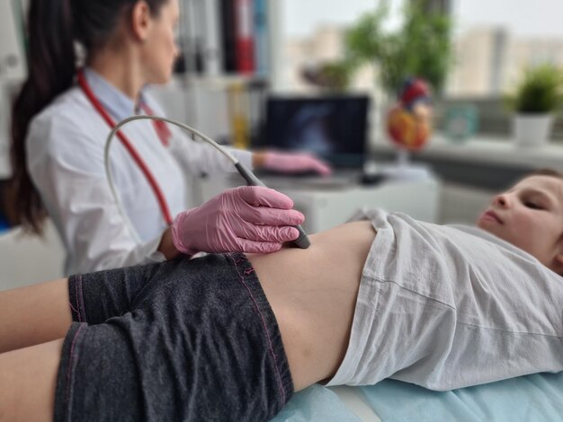 Foto el médico hace una ecografía de la cavidad abdominal de la niña usando un escáner en la clínica.