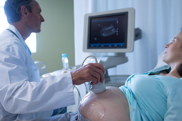 Foto médico haciendo una ecografía para una mujer embarazada en el hospital