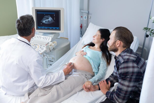 Foto médico haciendo una ecografía para una mujer embarazada en el hospital
