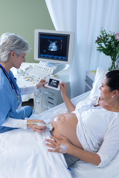 Foto médico haciendo una ecografía para una mujer embarazada en el hospital