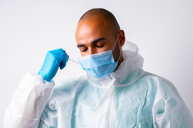 Médico hombre afroamericano poniéndose uniforme protector contra el fondo blanco, Retrato