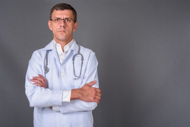 Médico homem bonito com cabelo curto contra um fundo cinza