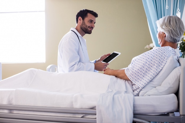 Foto médico homem discutindo relatório médico sobre tablet digital com paciente do sexo feminino sênior na enfermaria