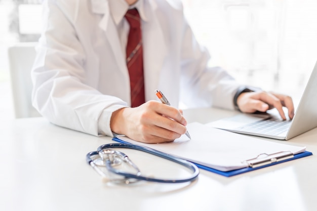 Médico homem trabalhando na mesa com o laptop.