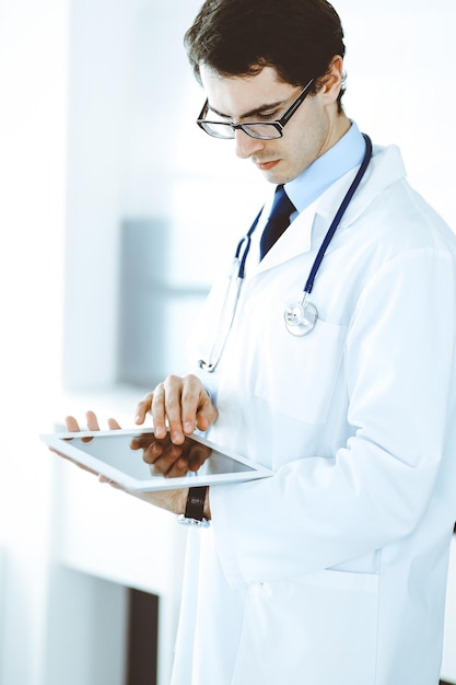 Médico homem usando computador tablet para pesquisa de rede ou tratamento de doenças virtuais. Serviço médico perfeito na clínica. Medicina moderna, dados médicos e conceitos de saúde.