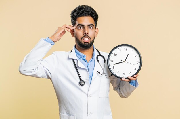 Médico indiano com ansiedade a verificar a hora no relógio a atrasar-se para o trabalho a atrasar o prazo