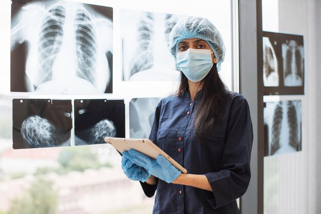 Médico indiano com máscara e boné usando um comprimido para verificar os raios-x