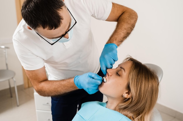 El médico inserta la bandeja de impresión y hace el molde de dientes al paciente en odontología antes de la implantación dental Procedimiento de creación de coronas y alineadores de prótesis dentales