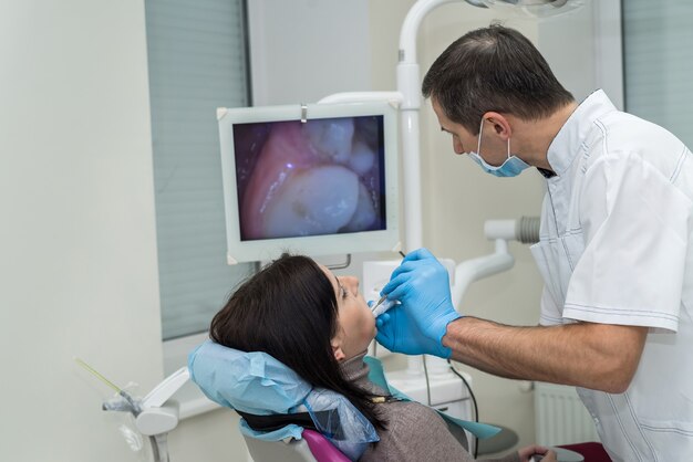 Médico inspecionando os dentes do paciente com espelho de perto