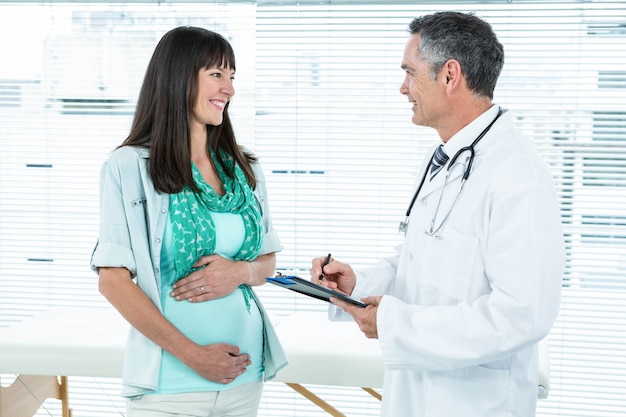 Médico interactuando con una mujer embarazada en la clínica durante el chequeo de salud