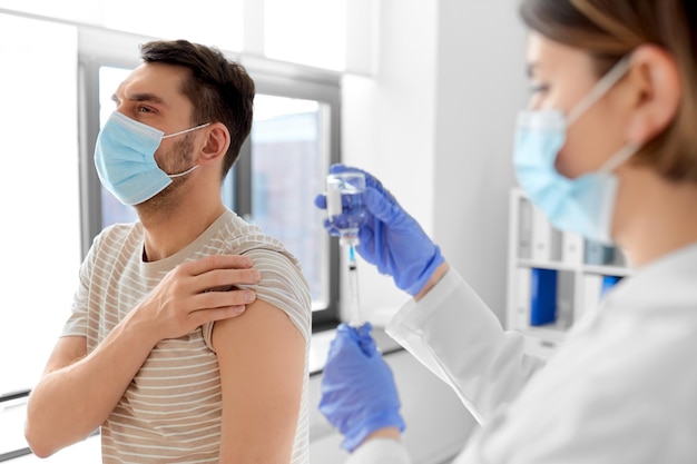 médico con jeringa vacunando al paciente masculino
