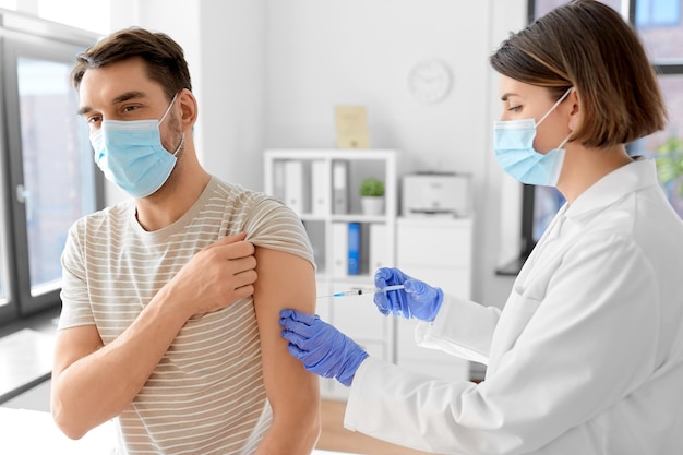 médico con jeringa vacunando al paciente masculino