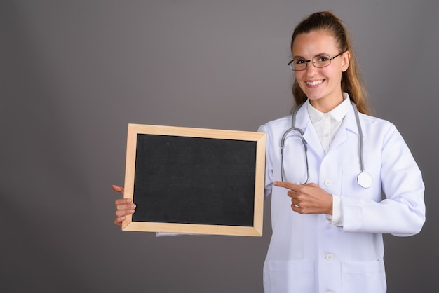 Médico jovem bonita contra fundo cinza