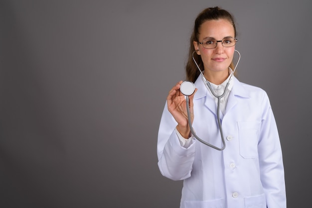 Médico jovem bonita contra fundo cinza