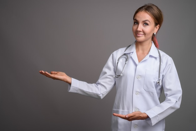 Médico jovem bonita contra parede cinza