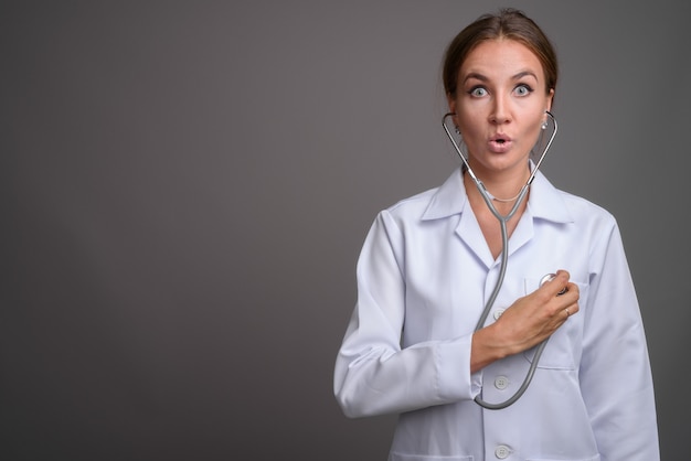 Médico jovem bonita contra parede cinza