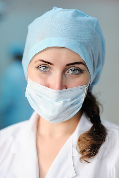 Médico jovem bonita de chapéu médico e máscara estéril