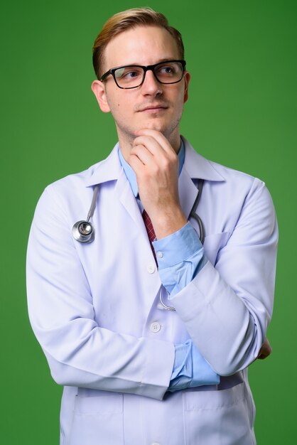 Foto médico jovem bonito com cabelo loiro contra fundo verde