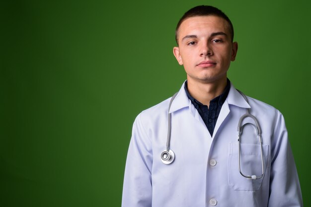 Médico jovem bonito contra fundo verde