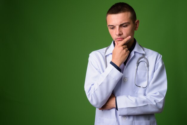 Médico jovem bonito contra fundo verde