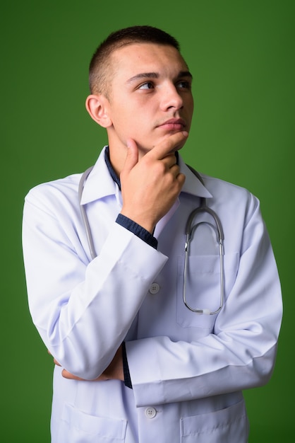 Médico jovem bonito contra fundo verde