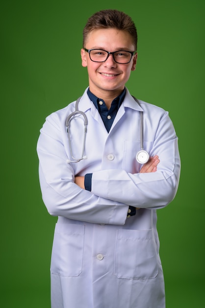 Médico jovem bonito contra fundo verde