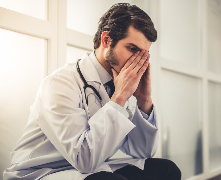 Foto médico jovem cansado no casaco branco está cobrindo seu rosto.