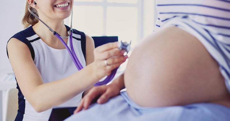 Foto médico jovem com estetoscópio e tablet falando com mulher grávida no hospital