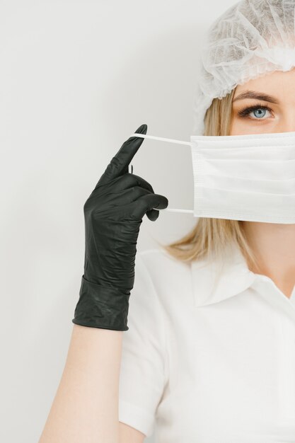 Médico jovem contemporâneo, colocar máscara protetora no rosto antes do procedimento médico