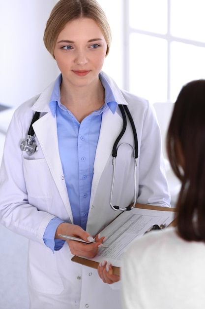 Médico jovem e paciente no exame médico no escritório do hospital. Blusa de cor azul de terapeuta fica bem. Conceito de medicina e saúde.