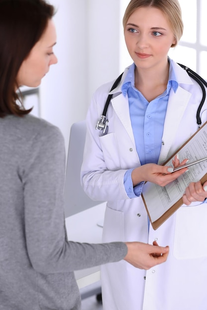 Médico jovem e paciente no exame médico no escritório do hospital. Blusa de cor azul de terapeuta fica bem. Conceito de medicina e saúde.