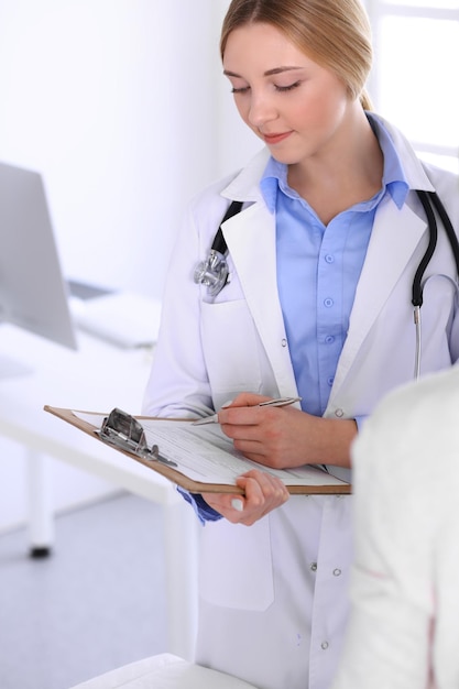 Médico jovem e paciente no exame médico no escritório do hospital. Blusa de cor azul de terapeuta fica bem. Conceito de medicina e saúde.