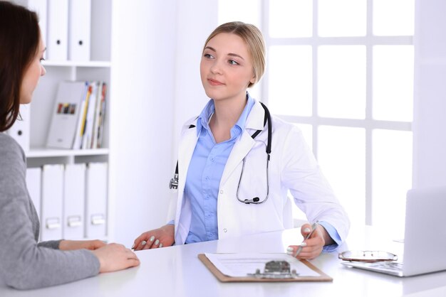 Médico jovem e paciente no exame médico no escritório do hospital. Blusa de cor azul de terapeuta fica bem. Conceito de medicina e saúde.