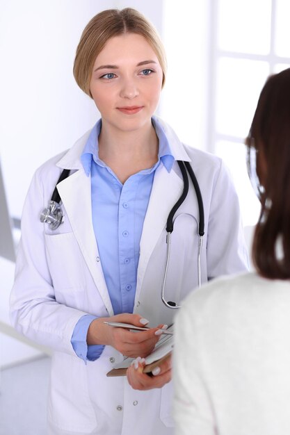 Médico jovem e paciente no exame médico no escritório do hospital. Blusa de cor azul de terapeuta fica bem. Conceito de medicina e saúde.