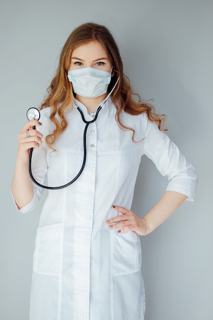 Médico jovem em um jaleco branco e máscara médica. O remédio