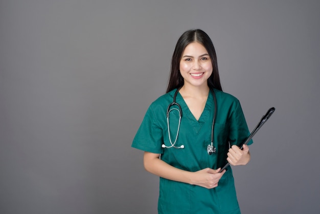 Médico jovem feliz mulher bonita vestindo uma bata verde está segurando documentos