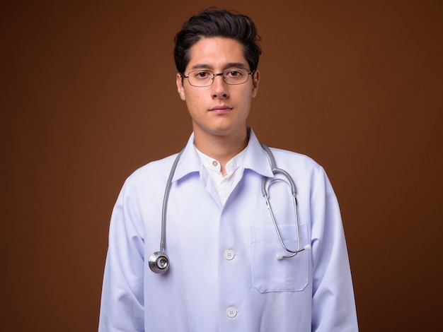 Médico jovem multiétnico contra um fundo marrom