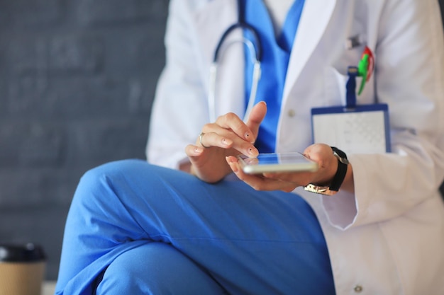 Médico jovem sentado com seu telefone Médicos de mulher