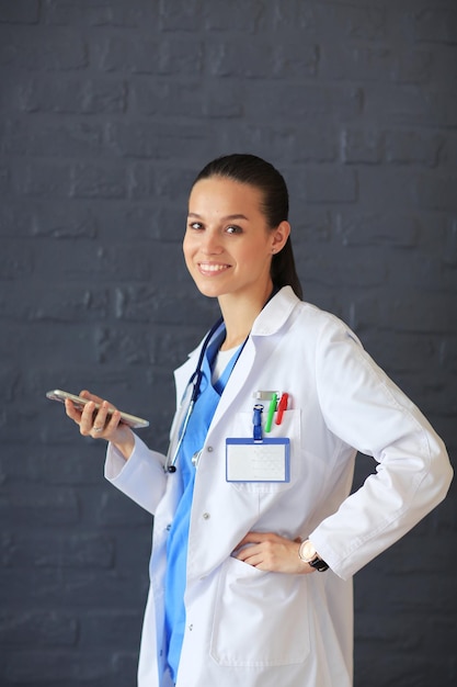 Médico jovem sentado com seu telefone Médicos de mulher