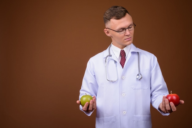 Médico jovem usando óculos em um fundo marrom