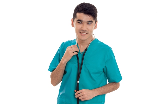 Médico joven alegre posando en uniforme aislado sobre fondo blanco en estudio