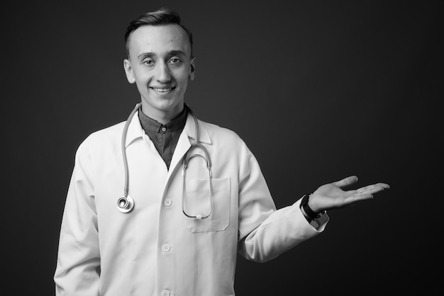 médico joven apuesto contra la pared gris. en blanco y negro