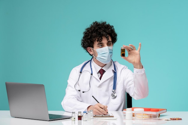 Médico joven y apuesto que trabaja en una computadora de forma remota en una bata de laboratorio mirando la medicina