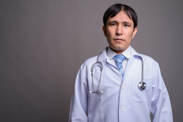 Foto médico joven asiático contra la pared gris