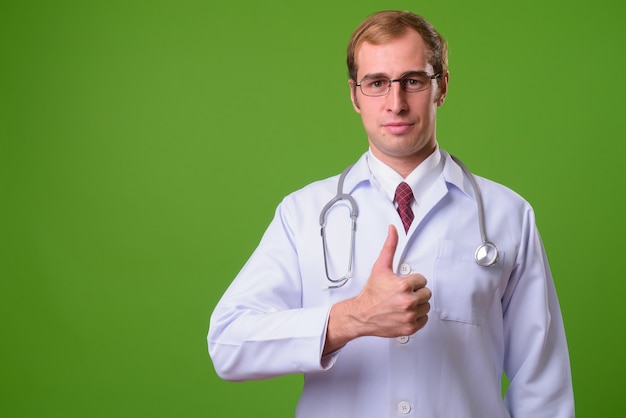 Médico joven contra la pared verde