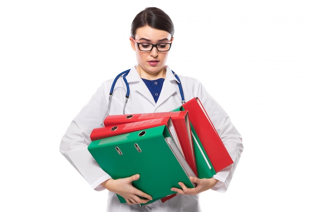 Médico joven enojado con estetoscopio con aglutinantes en sus manos en uniforme blanco sobre blanco