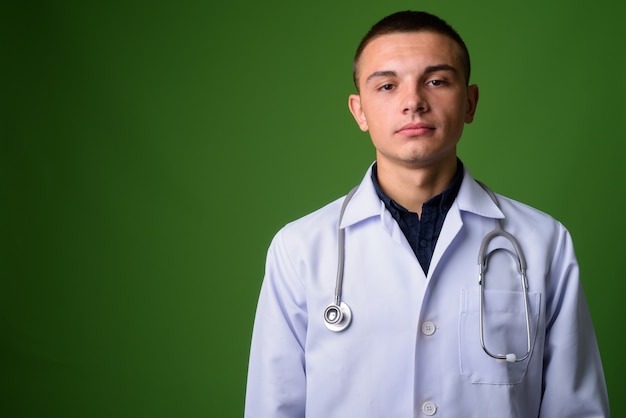 Médico joven guapo contra fondo verde