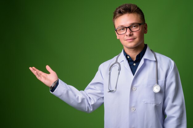 Médico joven guapo contra fondo verde